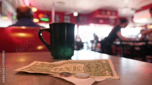 Tips, check and cup of coffee on the table of American diner. Waiters clean tables.