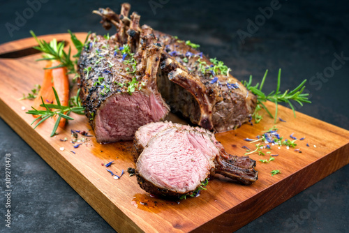 Foto Barbecue rack of lamb with carrot and herbs offered as closeup on a modern desig