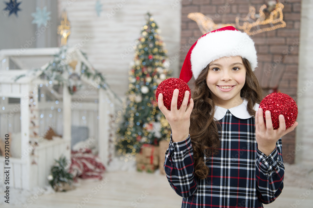 home and christmas tree decor. moring before xmas. happy new year. smiling child in santa hat. winter holiday activity. christmas shopping. small girl elf costume. trendy kid decorative xmas ball