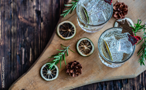 Ideas of winter drinks from gin and tonic for the new year. A bottle of gin and water tonic on a wooden table