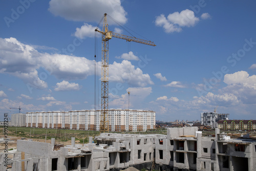 Construction site view including several cranes working on a building complex against cloudy sky