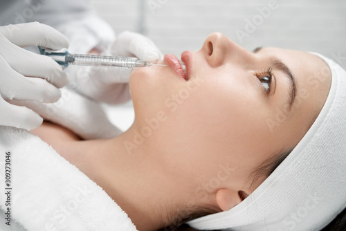 Cosmetologist keeping prick with collagen