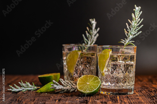 Gin and tonic with lime and ice on wooden table. Ideas of winter drinks