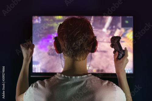 gamer with gamepad happy to win in the online game, the player with headphones in front of the monitor