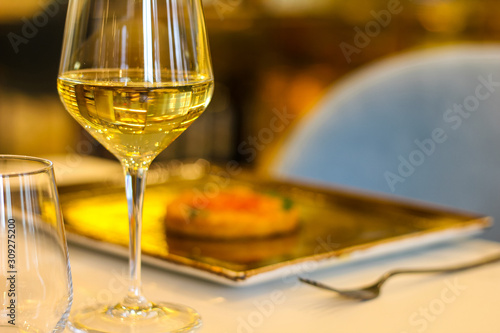 detail of glass of white wine with risotto dish in refined Italian restaurant