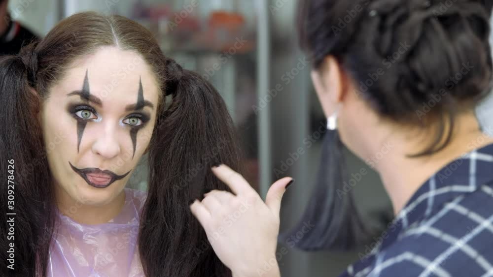 Easy Halloween Makeup. Emotions of the client and the master. The girl laughs and covers her lips with her hand. Easy Halloween Makeup. Emotions of the client and the master. The girl laughs and covers her lips with her hand.