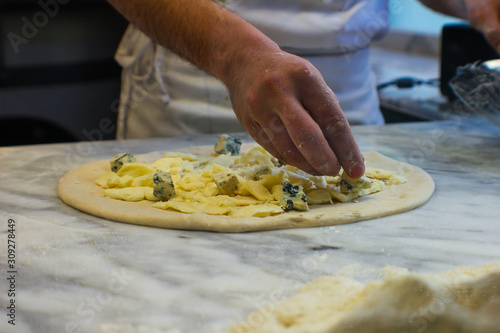 4 cheese pizza preparation with gorgonzola, smoked provola cheese, buffalo mozzarella and pecorino, in a typical Italian pizzeria