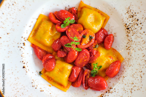 top view of plate of handmade Caprese ravioli served with red corbarino cherry tomato and marjoram
