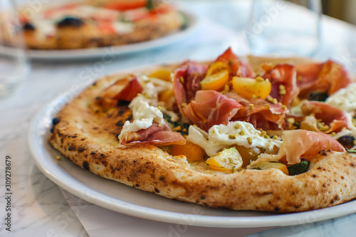 detail of pizza with corbarino yellow tomato, black Casertano pork ham, chopped pistachio and buffalo stracciatella