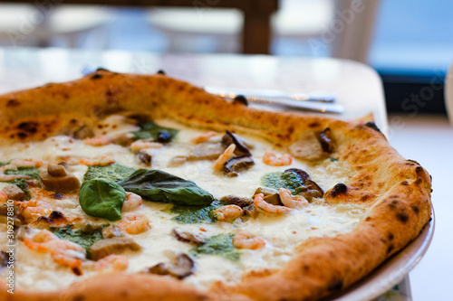 unusual pizza with porcini mushrooms sautéed with fior di latte, homemade basil pesto and pink prawns