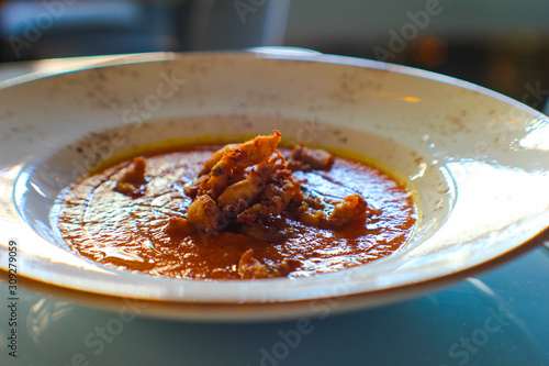 Neapolitan pumpkin soup, very special for its sweet taste, accompanied by fried squid, olive oil and oregano in a luxury Italian restaurant