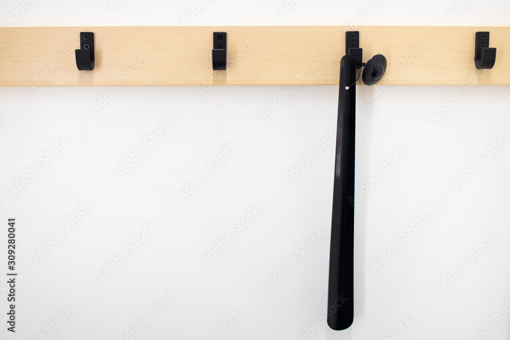 Black shoehorn on the wall and Coat hooks in the dressing room. Clothes fitting. Concept of clothing store. Retail shop in mall. Storage things in the wardrobe. Black shoehorn on the wall and Coat hooks in the dressing room. Clothes fitting. Concept of clothing store. Retail shop in mall. Storage things in the wardrobe.