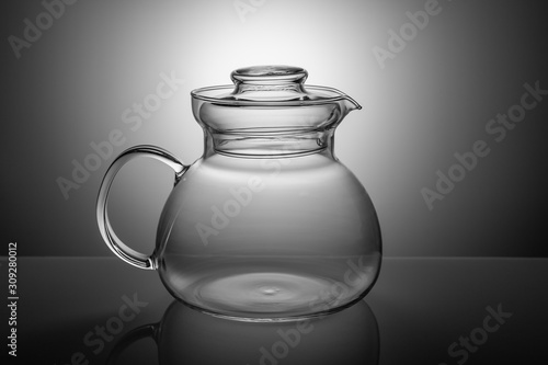 Glass teapot for drinks on a gradient gray background.