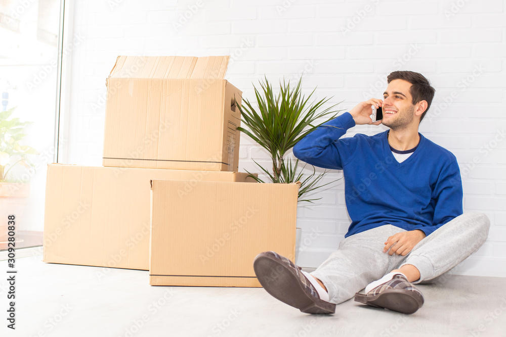 young man in the apartment with moving and mobile phone young man in the apartment with moving and mobile phone