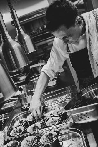 Head chef cooks prepares food, a cook cookds food in a restaurant in a kitchen, bw photo, black&white