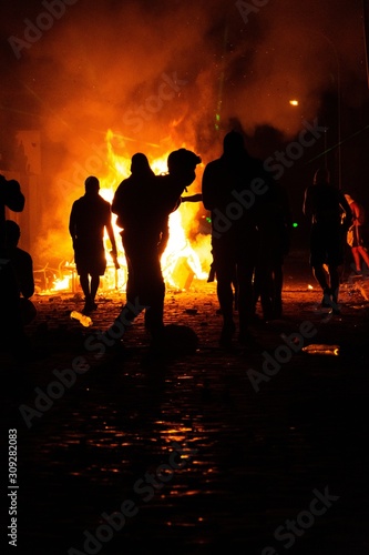 Vertical shot of silhouettes of people and a fire during the protests in Santiago de Chile photo