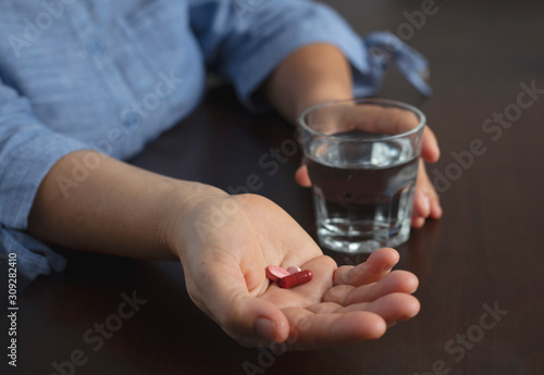 Woman holding glass of water and pack of pills