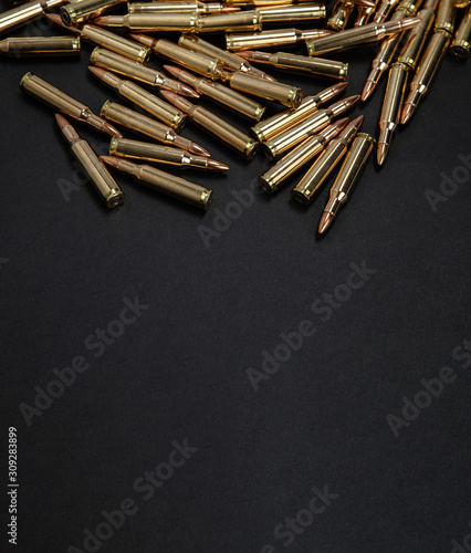 Cartridges for weapons on a dark background. Shiny brass ammo on black. Military background.