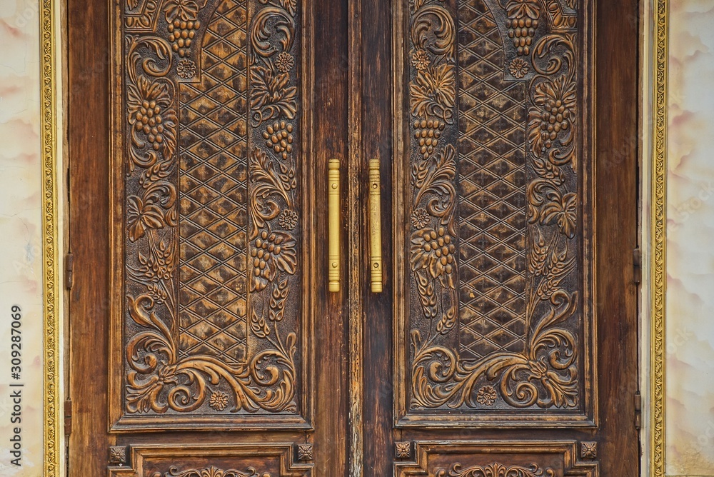 old brown wooden door with a pattern on a gray concrete wall