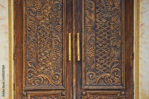 old brown wooden door with a pattern on a gray concrete wall