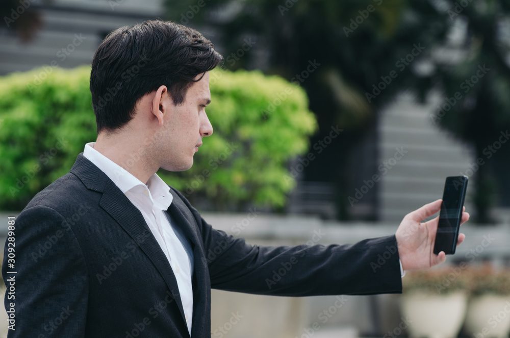 Portrait of young Businessman in black suit using a mobile phone for a video call with partners or selfie Portrait of young Businessman in black suit using a mobile phone for a video call with partners or selfie