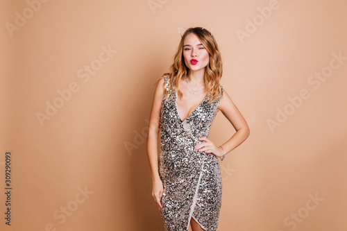 Tablou pe pânză Elegant caucasian woman with curly hairstyle posing with kissing face expression at chrismas party