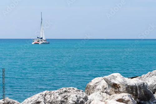 Catamaran cruise sailing on coast of tropical Caribbean island. Tourists  people enjoying sunny summer day on the ocean water. Beautiful blue low tide sea on holiday weekend. Vacation leisure activity