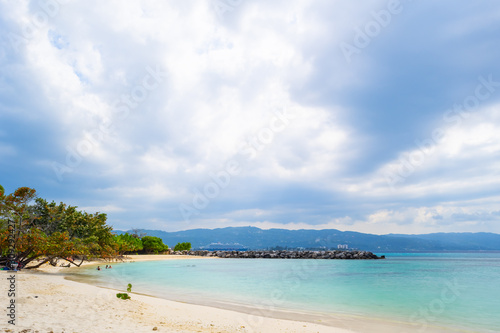 Beautiful clean Caribbean island beach on the coast of Montego Bay  Jamaica. Local people  tourists having a relaxing weekend morning in this scenic setting. White sand and clear turquoise waters.