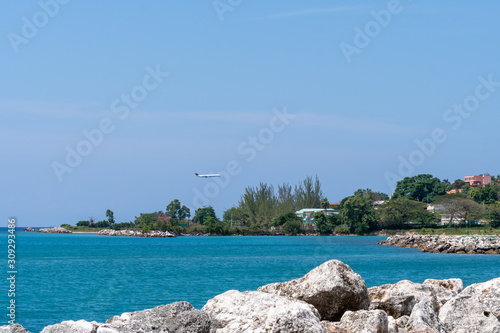 Coastline landscape view in Montego Bay, Jamaica with aircraft landing at Sangster International Airport (MBJ) in background. Scenic ocean water coast on tropical Caribbean island. photo