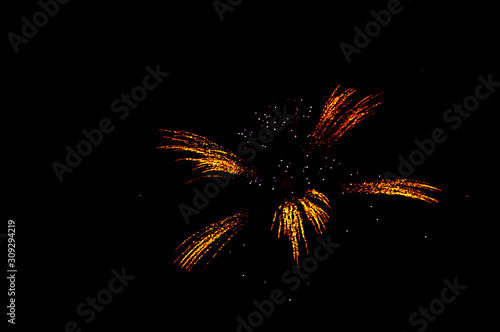 Yellow and red fireworks in the shape flower on the right side on a black background.