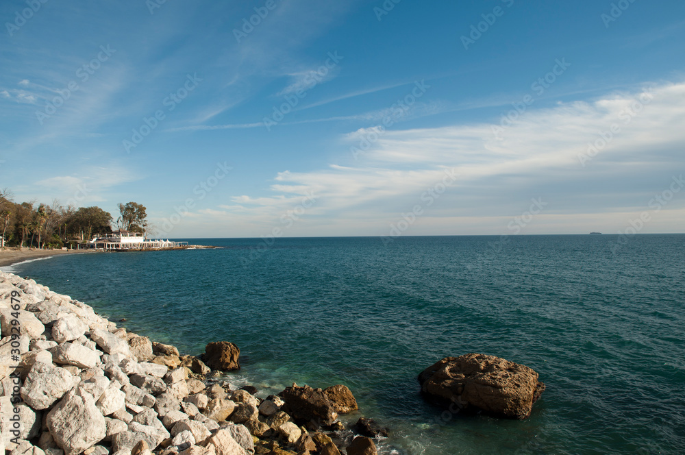 beaches malaga blue sky with soft clouds rocks and trees in the background. baleario Baños del Carmen