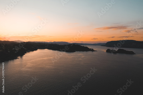 Drone shot of sunset in Bergen, sun reflection in water and silhouette mountains