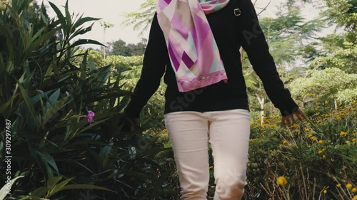 Attractive young Muslim woman enjoying view of green park with beautiful flowers at Cameron Highlands, Pahang
