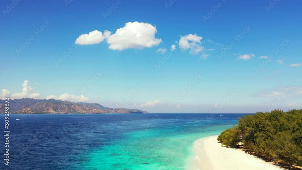 Paradise exotic beach with white sand washed by tranquil blue turquoise sea under a bright blue sky with overhanging white clouds in Bali Paradise exotic beach with white sand washed by tranquil blue turquoise sea under a bright blue sky with overhanging white clouds in Bali