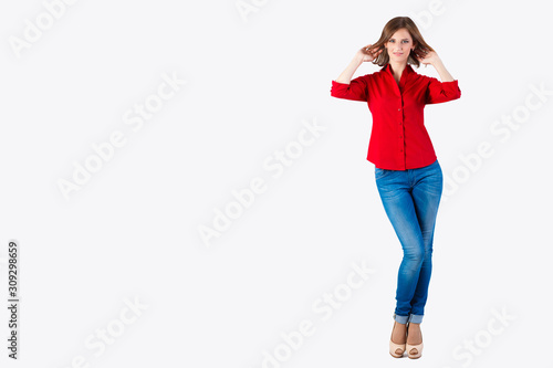 Portrait of beautiful smiling young woman standing in a red shirt and blue jeans isolated on white background. Space for text. Girl with a beautiful smile. Studio isolated. Copy space