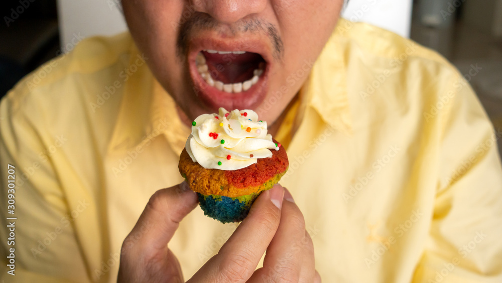 Asian men wearing glasses eating deliciously cupcakes Asian men wearing glasses eating deliciously cupcakes