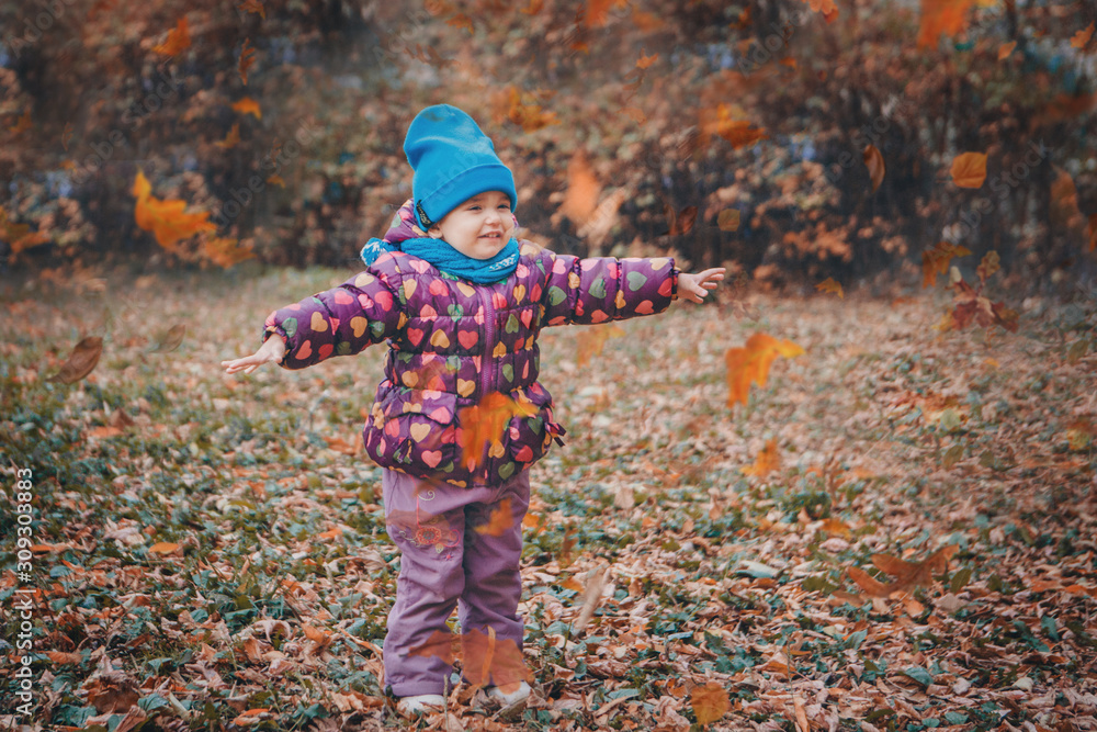 Naklejka premium a small child in a warm suit walks in the woods. autumn park. The concept of children's fashion, accessories, outdoor walks