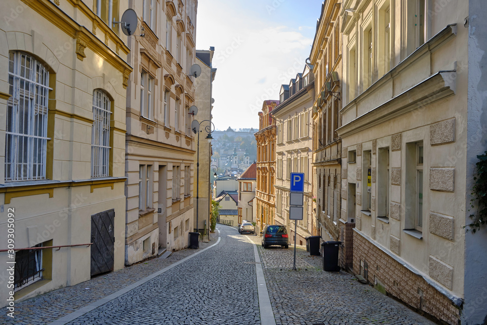Scenic view of narrow street of Karlovy Vary - small ancient touristic resort town near the border between Czech Republic and Germany. Beautiful summer sunny look of famous town among hills in Czechia