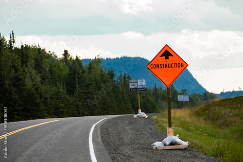 Temporary condition road signs, Construction work. on Canadian rural country roadside with pine trees forests background, warning orange symbol photo