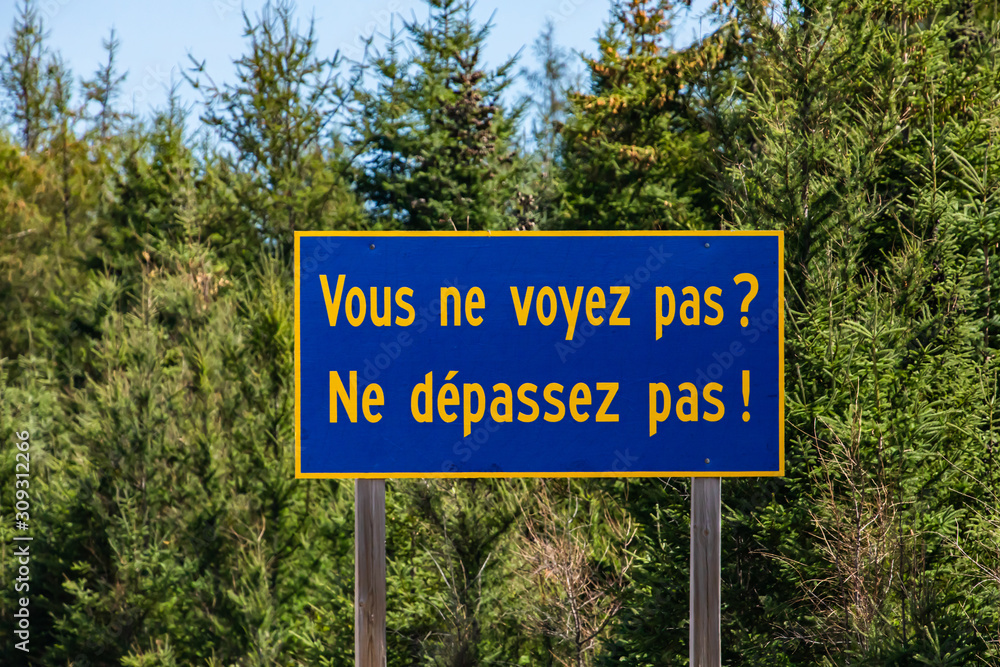 Blue Information Road Sign with french yellow writing, you cannot see not to exceed, on rural country roadside, trees background, Ontario, Canada Blue Information Road Sign with french yellow writing, you cannot see not to exceed, on rural country roadside, trees background, Ontario, Canada