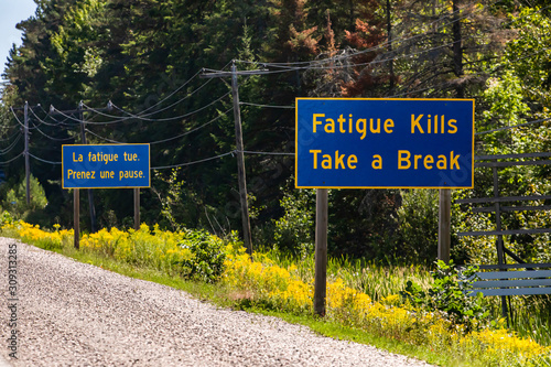 French and English Information road blue signs, tiredness kills. take a break. Canadian rural country roadside, Ontario, Canada photo