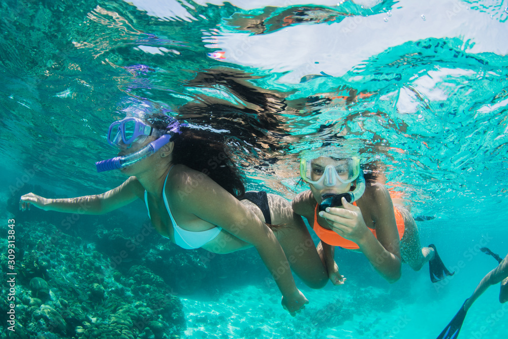two Young girls snorkeling in blue clear waters having fun at caribbean beach