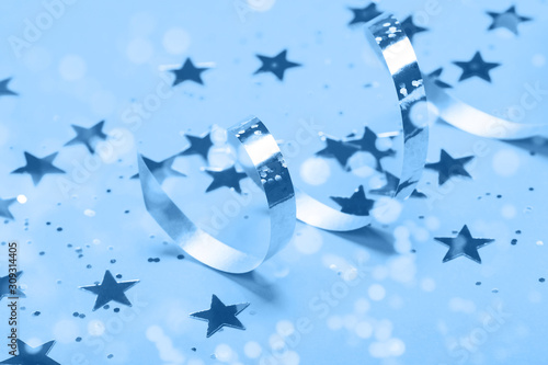 Shiny party streamers and stars on the blue background. Close up. The concept of celebrations, the Day of St. Valentine, Christmas, New Year, holiday, birthday, etc.