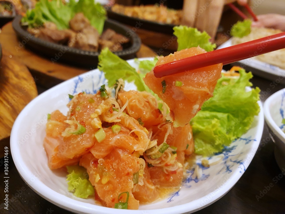 Japanese food style, Selective focus of chopsticks holding salmon salad, Salmon sashimi is Japanese traditional, Selective focus Japanese food style, Selective focus of chopsticks holding salmon salad, Salmon sashimi is Japanese traditional, Selective focus