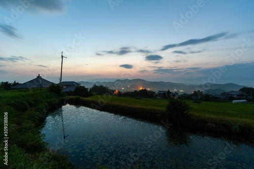 夜明けの空と農村の溜池