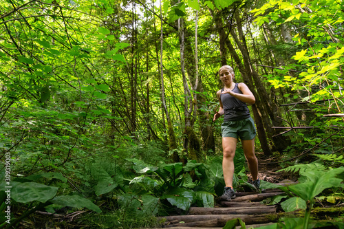 Adventurous Girl Trail Running in the Woods during a vibrant summer day. Taken in Deep Cove, North Vancouver, British Columbia, Canada.