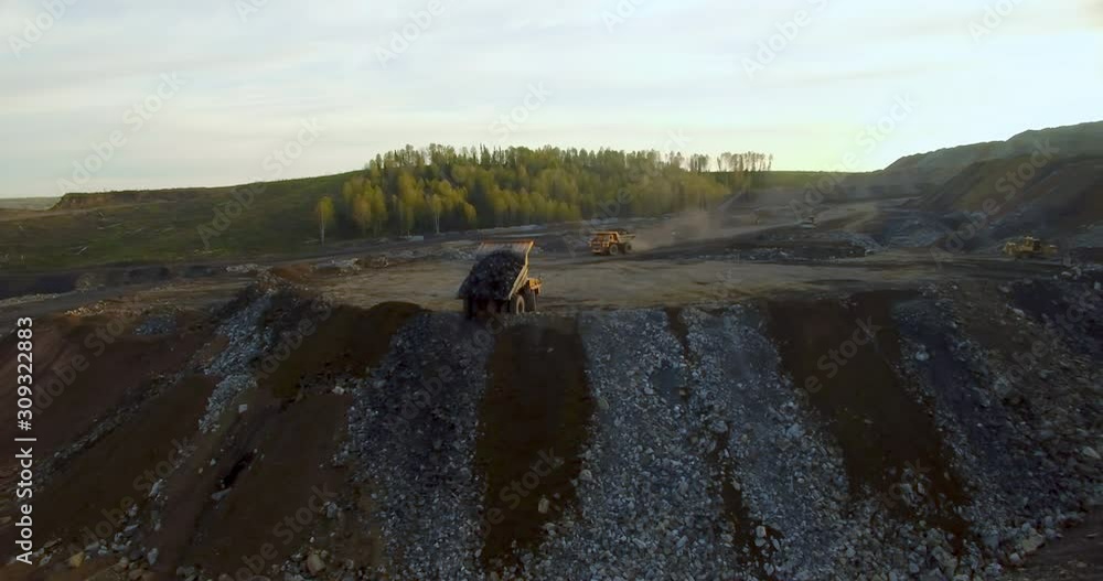 Aerial view from drone Yellow dump truck unloads land and rocks Aerial view from drone Yellow dump truck unloads land and rocks
