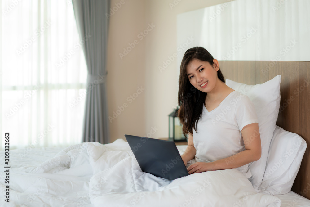 Portrait of beautiful Asian woman relax using laptop and in bedroom. Smile happy asian girl online shopping at home Education e-commerce freelance technology connected asia people concept Portrait of beautiful Asian woman relax using laptop and in bedroom. Smile happy asian girl online shopping at home Education e-commerce freelance technology connected asia people concept