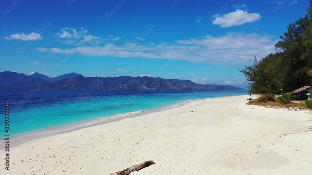 Quiet empty beach with white sand washed gently by waves coming from blue azure sea at sunrise with vivid colors of bright sky background in Bali Quiet empty beach with white sand washed gently by waves coming from blue azure sea at sunrise with vivid colors of bright sky background in Bali