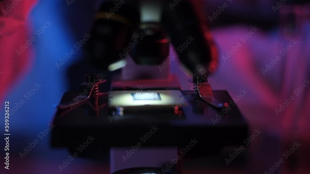 researcher in scientific and technical laboratory with neon light examines ultra modern computer processor through microscope. Scientific industrial research. concept of modern technological future researcher in scientific and technical laboratory with neon light examines ultra modern computer processor through microscope. Scientific industrial research. concept of modern technological future